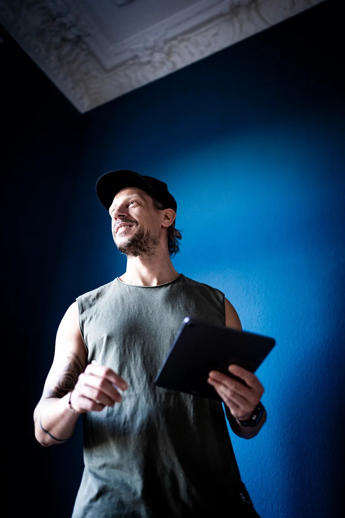 Alex with a tablet in front of a blue wall